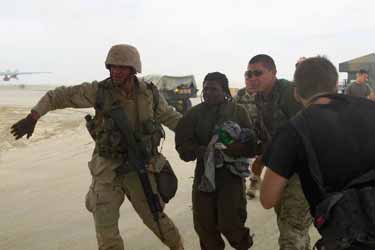 Former POW Shoshana Johnson, center, is escorted by U.S. soldiers to a waiting C-130 transport